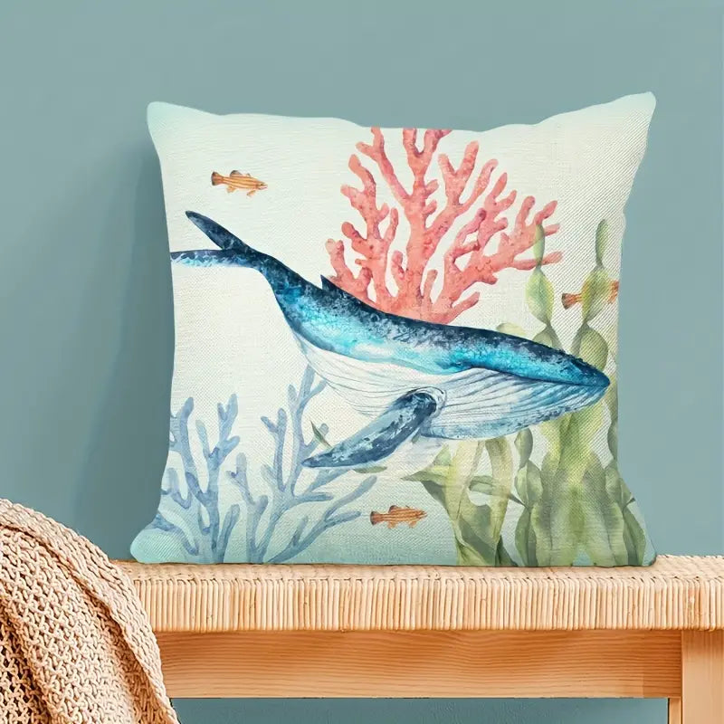 Square coastal pillow cover featuring a detailed watercolor illustration of a blue humpback whale swimming among pink and blue coral reefs with sea grass and small tropical fish for nautical décor - 18x18 - Coastal Pillows Plus