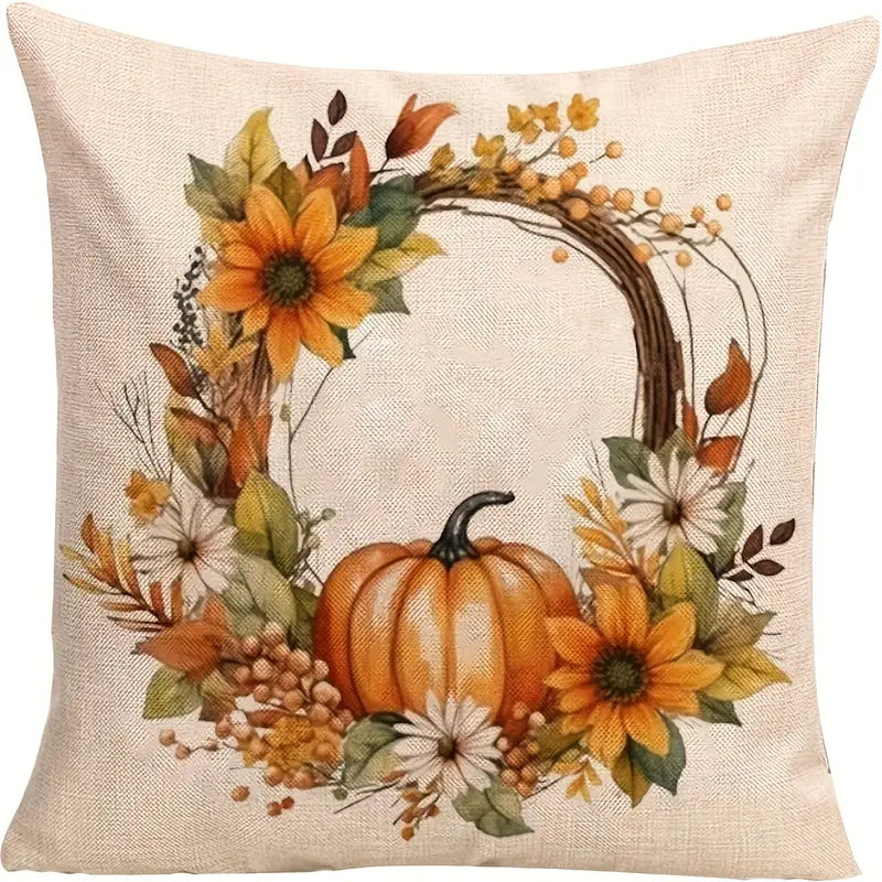 Linen pillow cover with orange pumpkin centered in wreath of sunflowers, daisies, berries, and autumn leaves.