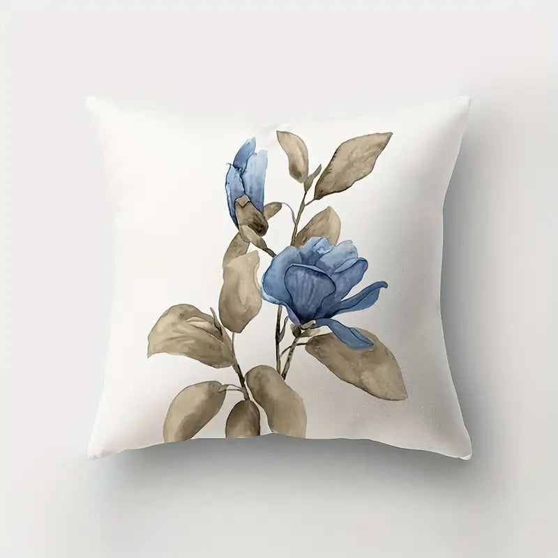 Illustrative 18x18 inch pillow cover with a watercolor-style blue Magnolia blossom and soft tan leaves on a crisp white background, styled on a chair for floral décor – Coastal Pillows Plus.
