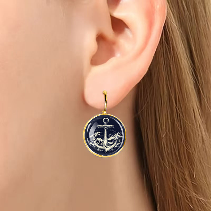 Classic golden alloy anchor earrings featuring dark blue and white glass for a traditional nautical décor.