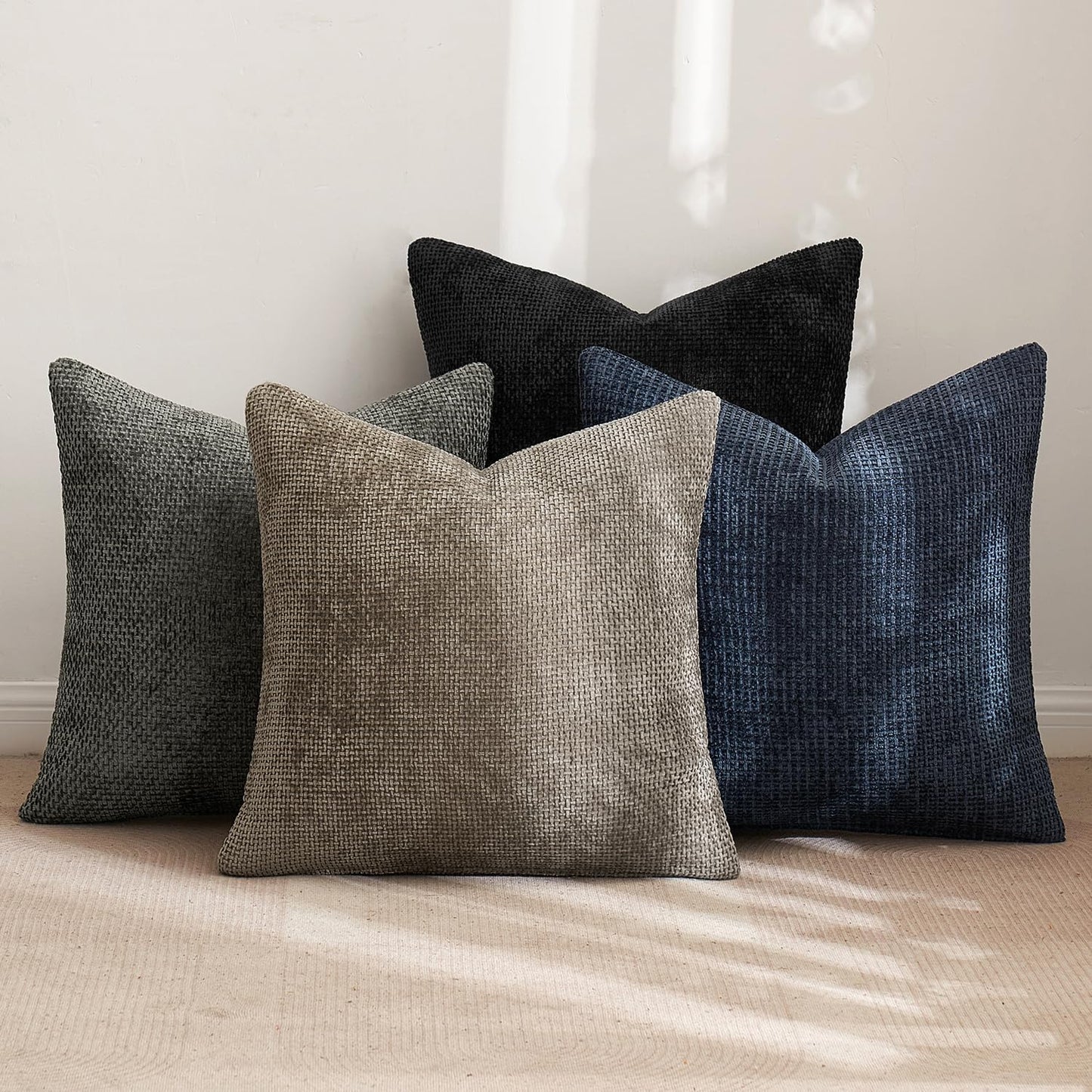 Naturally Toned 18x18 inch pillow covers in Warm Taupe, Slate Grey, Pebble, and Black showing a dense woven grid pattern, styled on a neutral sofa for coastal décor – Coastal Pillows Plus.