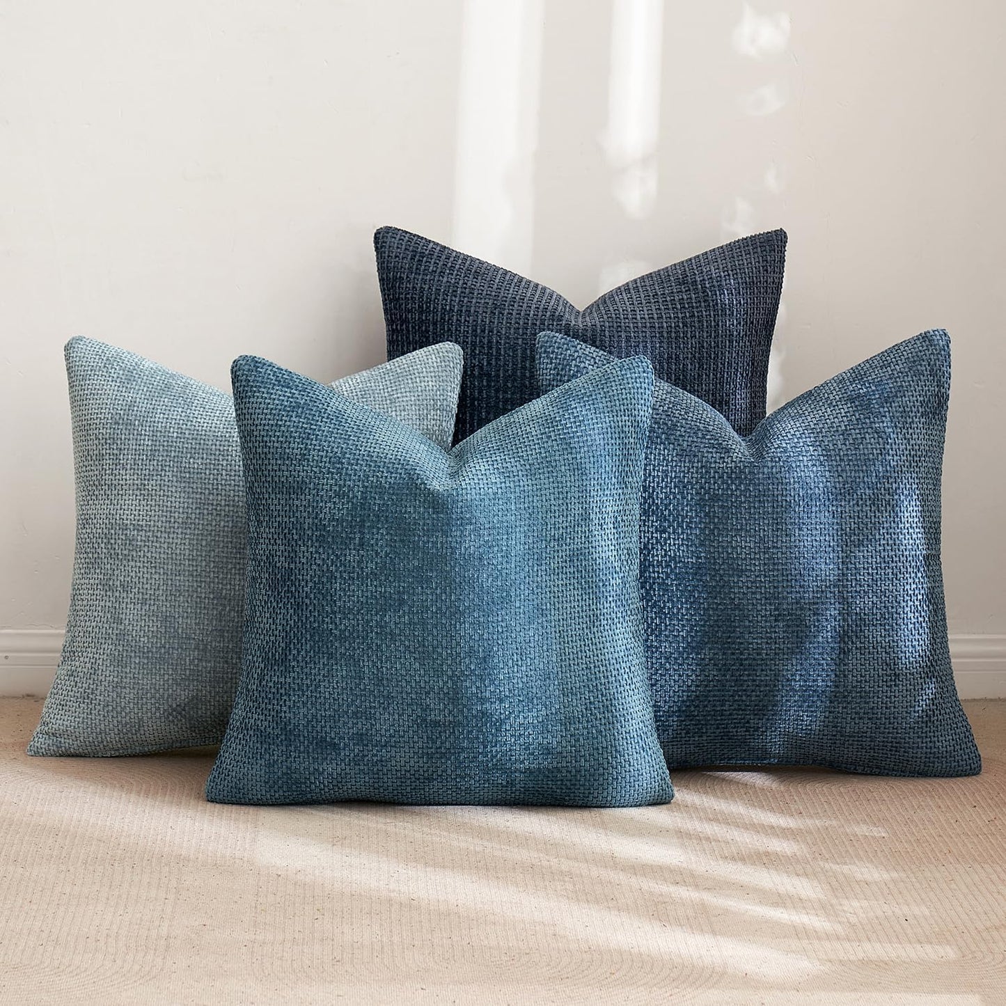 Textured 18x18 inch pillow covers in Storm Blue, Chambray, Steel, and Indigo showing a dense woven grid pattern, styled on a neutral sofa for coastal décor – Coastal Pillows Plus.