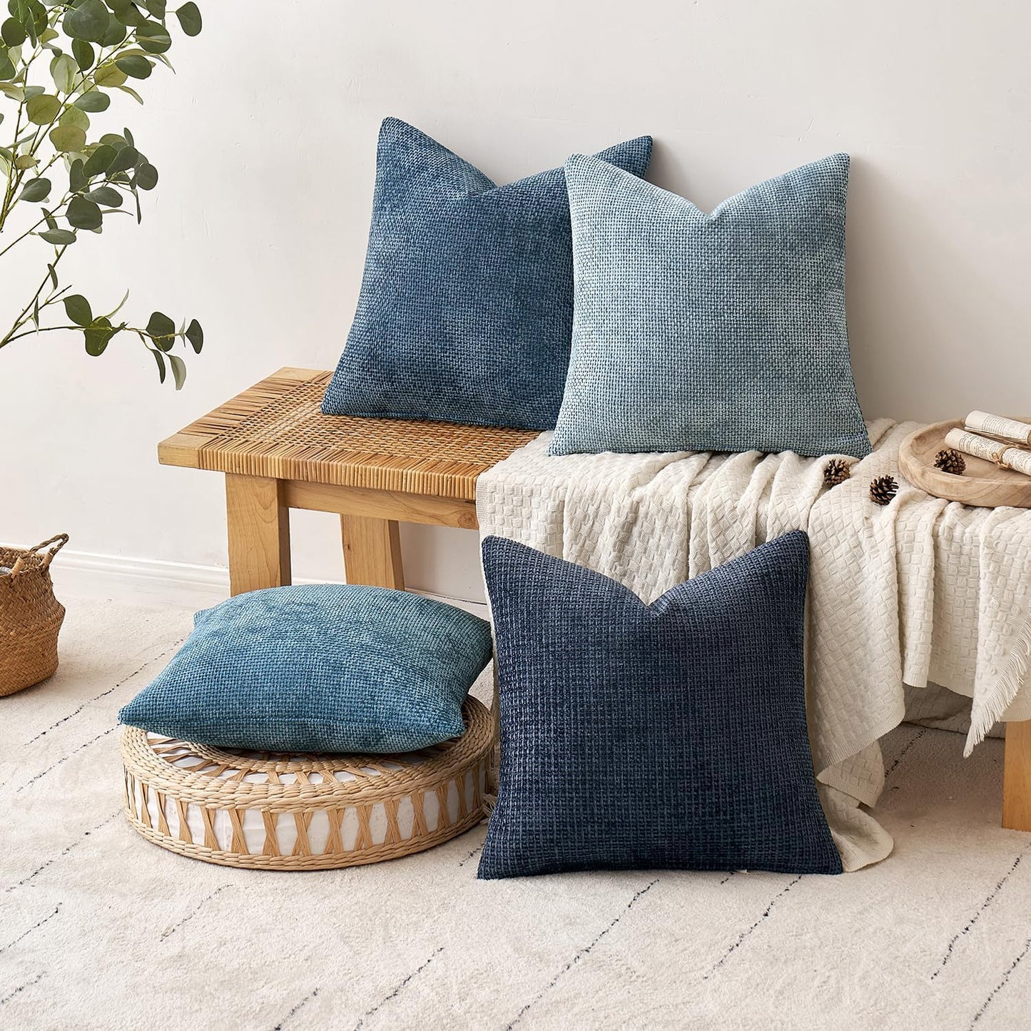 Textured 18x18 inch pillow covers in Storm Blue, Chambray, Steel, and Indigo showing a dense woven grid pattern, styled on a neutral sofa for coastal décor – Coastal Pillows Plus.