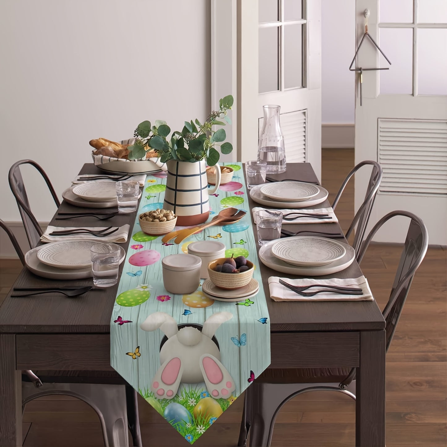 Fetching 13x90 inch triangular Easter table runner featuring a bunny bottom diving into a hole, with eggs and butterflies on a blue wood-grain background, styled on a table for spring holiday décor – Coastal Pillows Plus