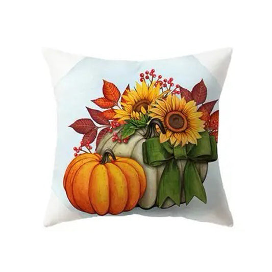 Pillow cover with sunflowers arranged beside pumpkins and autumn leaves on a light background.