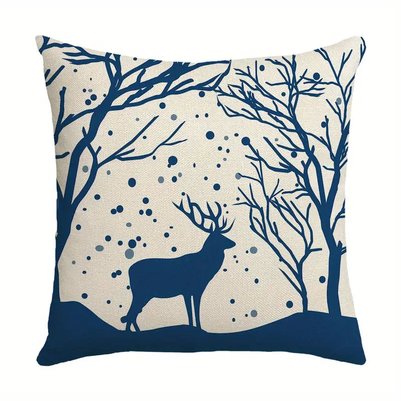 Outdoor winter pillow cover with blue deer silhouette, bare trees, and falling snow on a neutral background