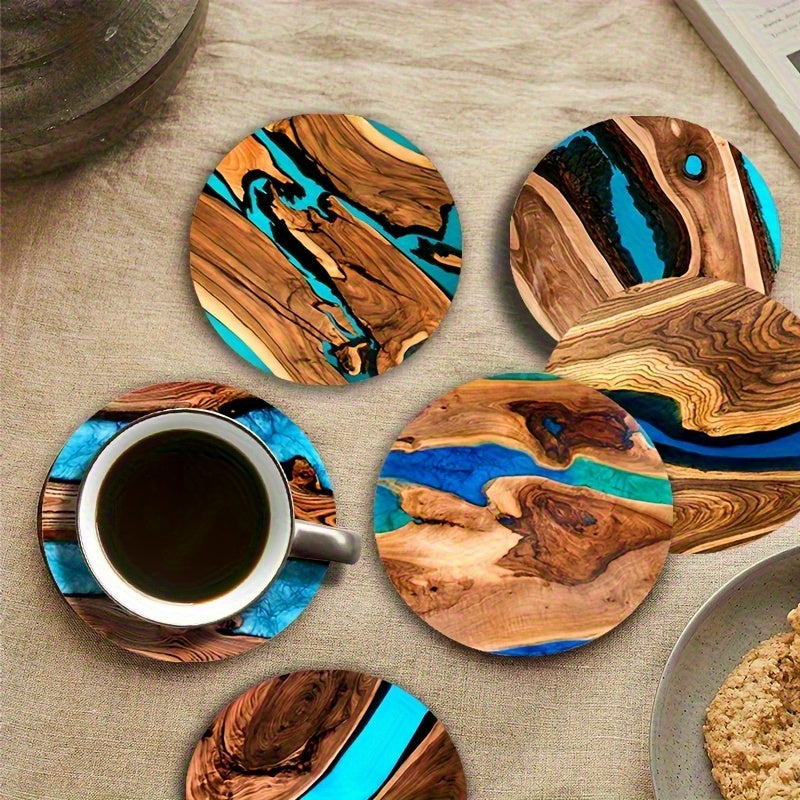 Round wood grain coasters with blue and green resin-style abstract designs on a table with a coffee cup.