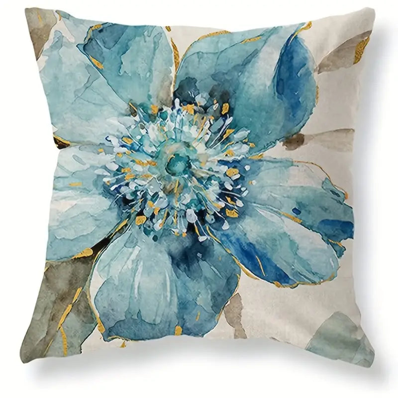 Decorative linen pillow cover featuring a large blue watercolor-style flower with soft neutral background and subtle gold detailing.