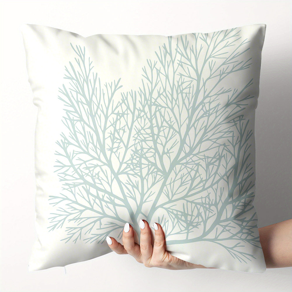 Pillow with tree branch pattern held by a hand on a light background