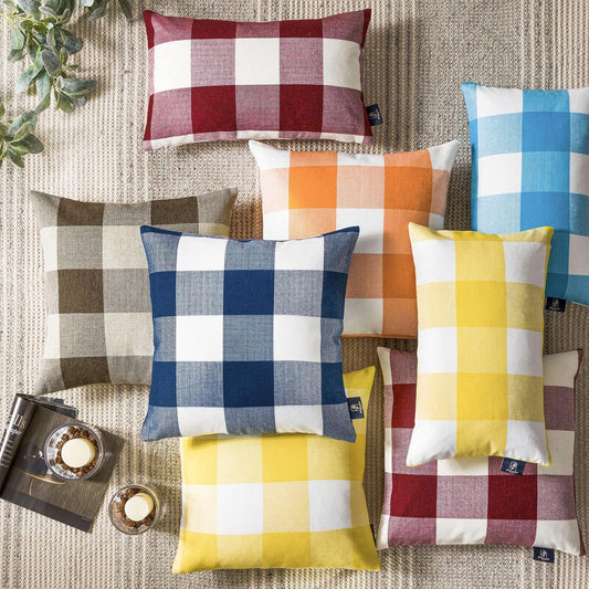 Classic multi-colored buffalo check gingham plaid pillow covers in navy, red, yellow, orange, and blue arranged on a neutral rug for farmhouse décor – Coastal Pillows Plus.