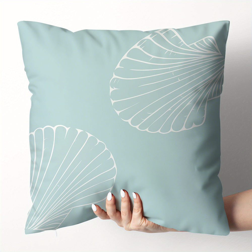 Light blue pillow with white leaf patterns held by a hand against a neutral background