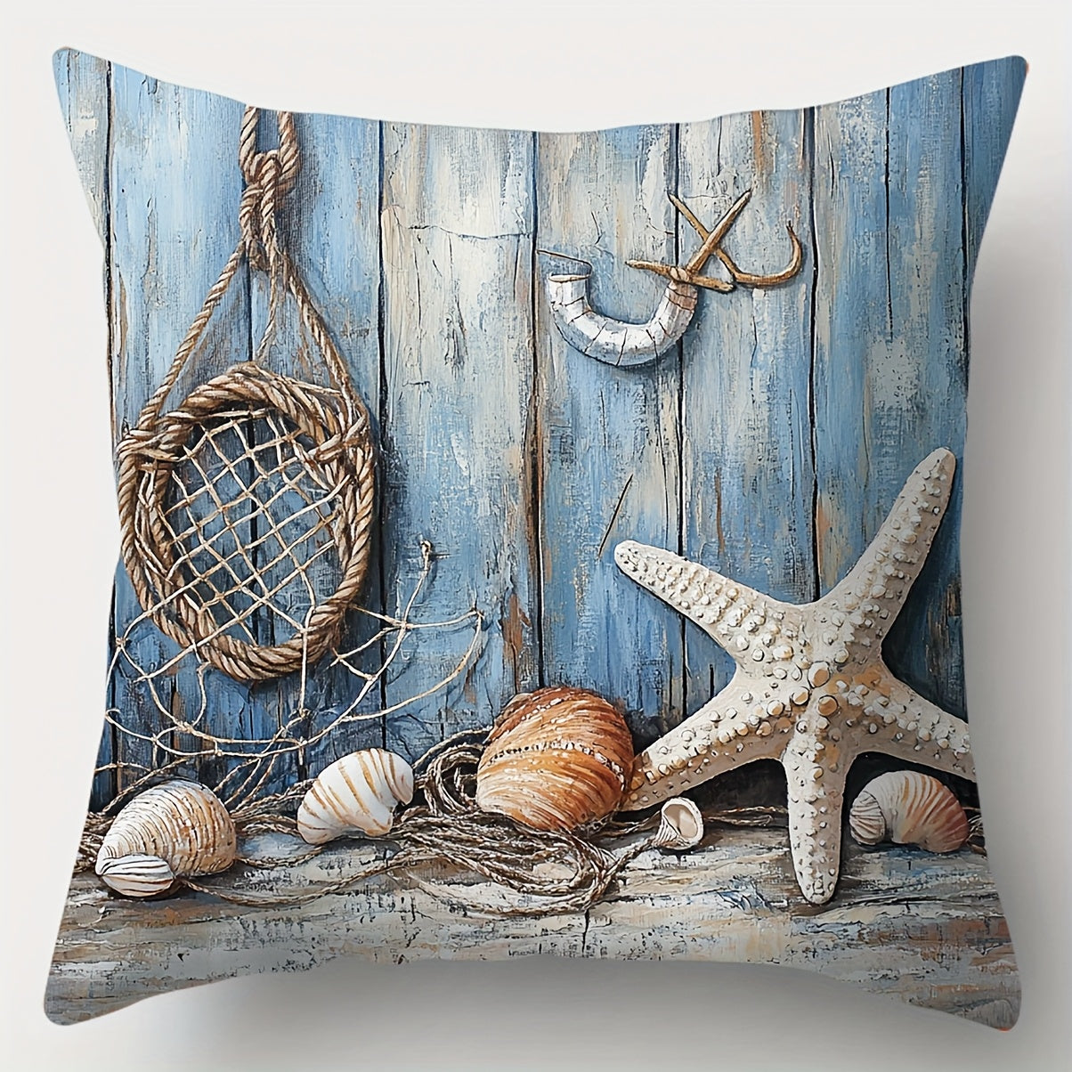 Coastal pillow cover featuring seashells and a starfish arranged with fishing net and rope against a weathered blue wood backdrop.