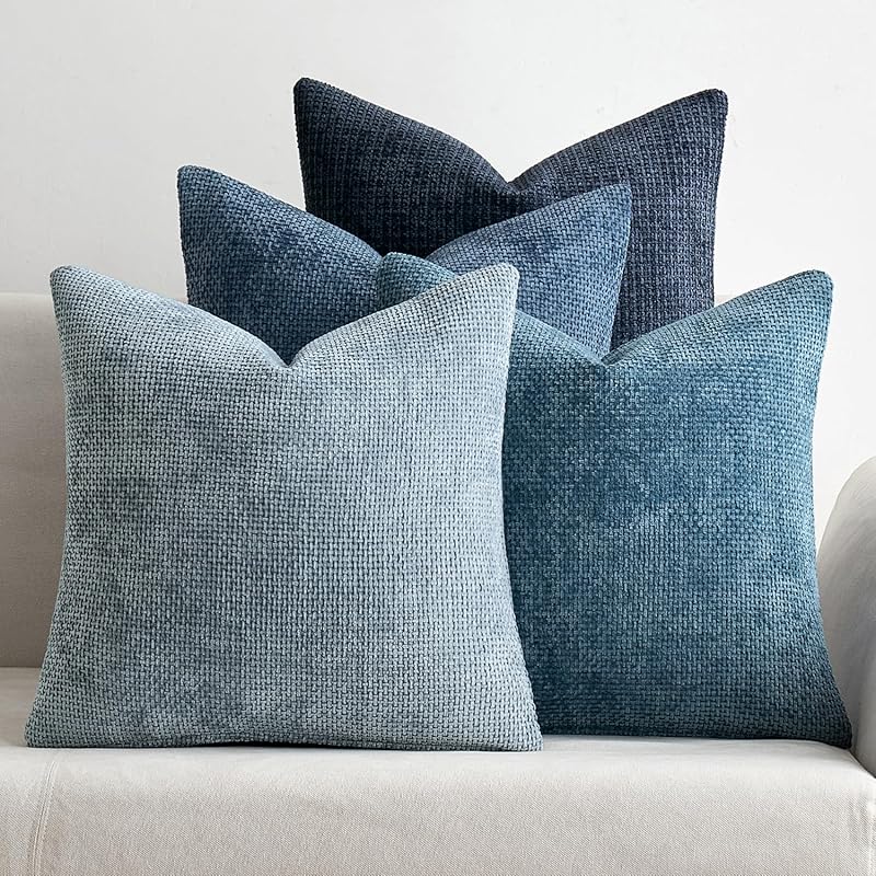 Textured 18x18 inch pillow covers in Storm Blue, Chambray, Steel, and Indigo showing a dense woven grid pattern, styled on a neutral sofa for coastal décor – Coastal Pillows Plus.