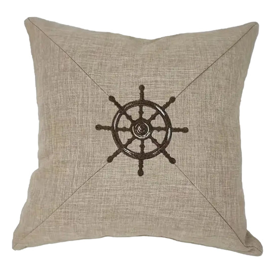 Neutral pillow cover with embroidered ship wheel design centered on textured fabric for coastal and nautical home decor.