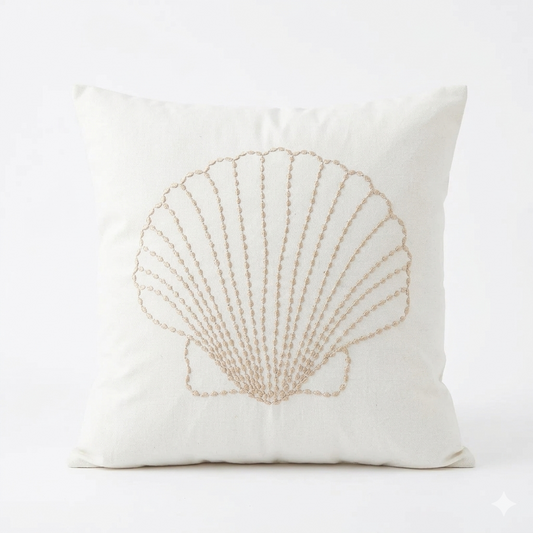 Neutral coastal pillow cover with embroidered scallop shell design on light fabric for beach house and coastal home decor.