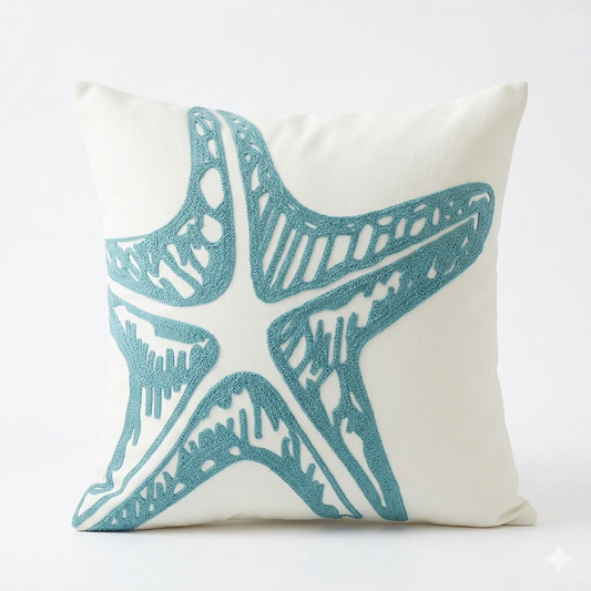 Coastal pillow cover with large blue embroidered starfish on a light fabric background for beach house and coastal home decor.