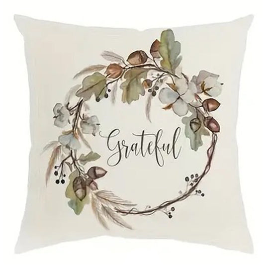 Linen pillow cover with “Grateful” text centered inside a watercolor wreath of leaves and acorns.