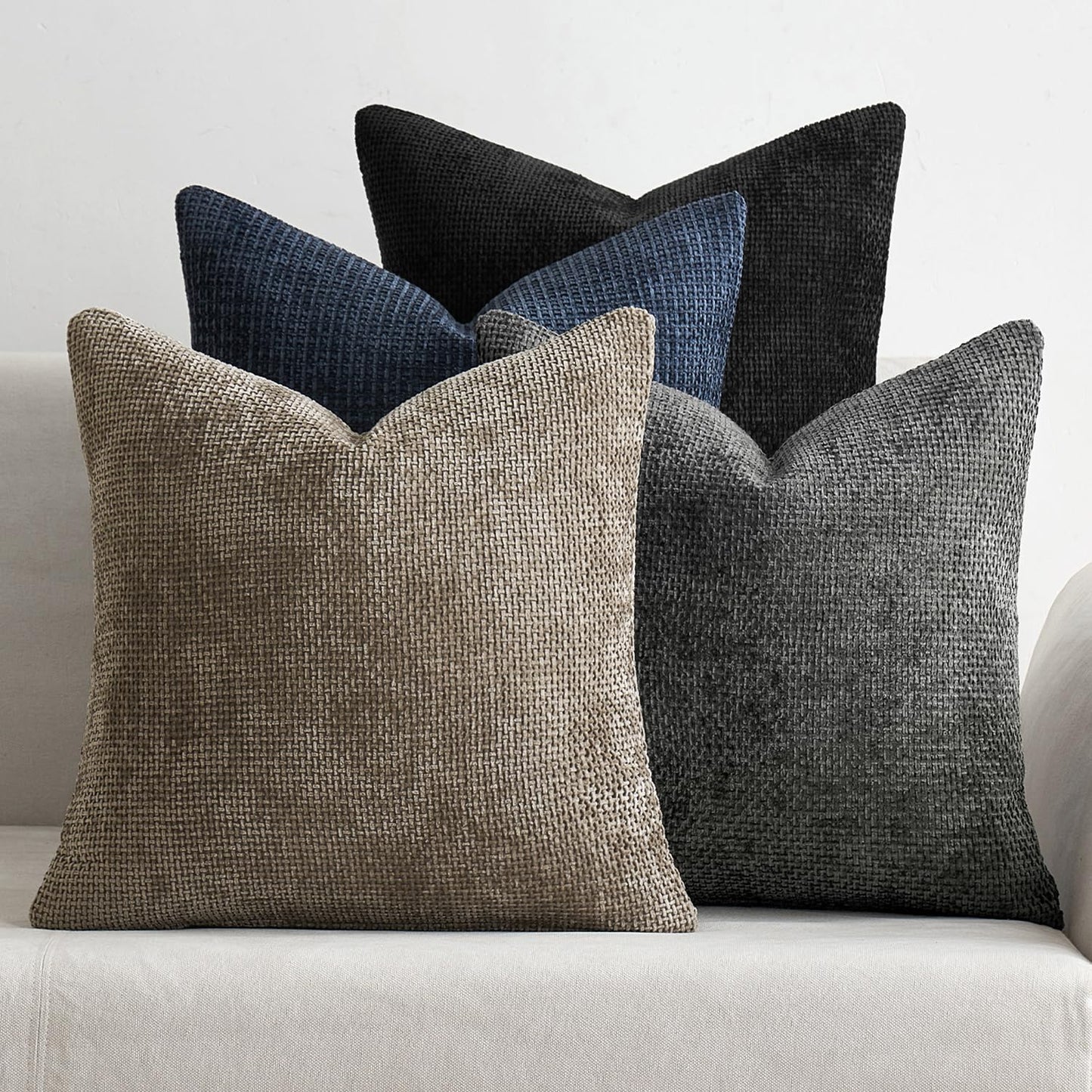 Naturally Toned 18x18 inch pillow covers in Warm Taupe, Slate Grey, Pebble, and Black showing a dense woven grid pattern, styled on a neutral sofa for coastal décor – Coastal Pillows Plus.