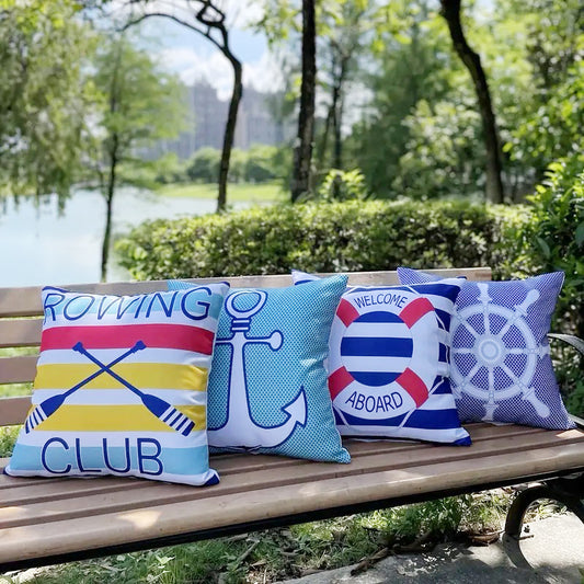 Set of four outdoor waterproof pillow covers with rowing oars, anchor, welcome aboard life ring, and ship helm nautical designs on a bench.