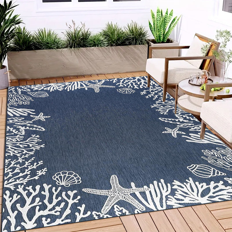 Coastal area rug featuring white starfish, coral, and seashell designs framing a deep navy blue center.