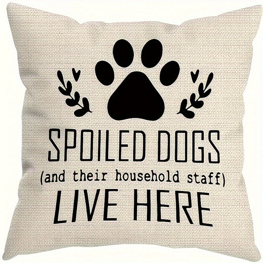 Decorative pillow with paw print and text 'Spoiled dogs (and their household staff) live here' on a beige background