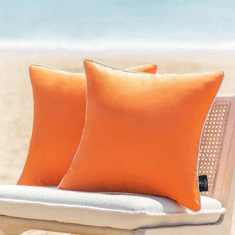 Solid orange waterproof outdoor pillow cover displayed on a patio chair with a light cushion, suitable for outdoor seating and porch décor.