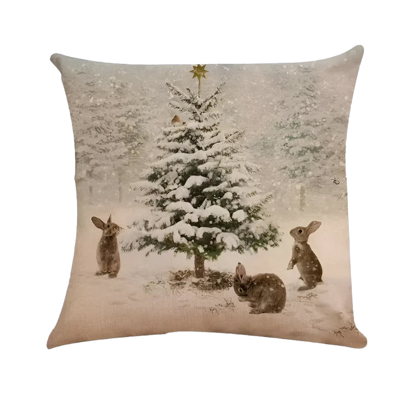 Winter pillow cover featuring snowy pine tree and rabbits in a winter forest scene.